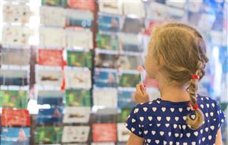 Little girl with lollipop near postcard kiosk
