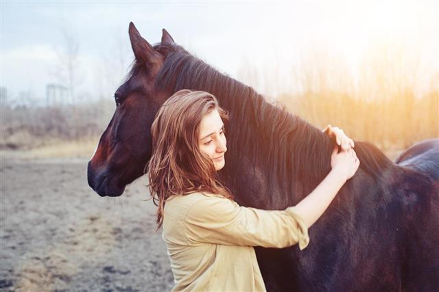 Beautiful young female walking and hugging with her horse outdoor