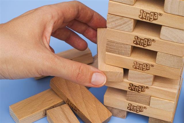 Human hand removing one block from Jenga tower
