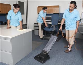 Women from janitorial service cleaning an office