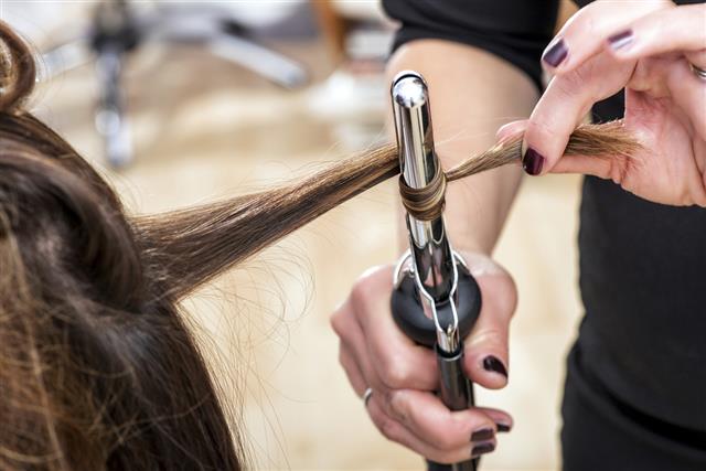 Hairstylist using a curling iron to firm ringlets