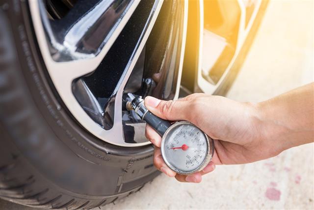 Close-Up Of Hand holding pressure gauge for car tire pressure