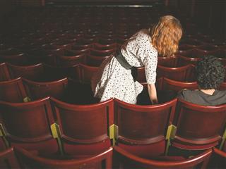 Woman taking her seat next to man in auditorium