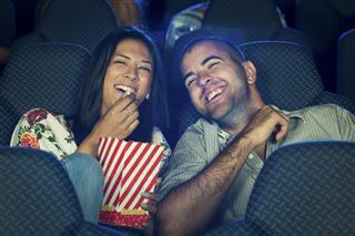 Couple eating popcorn in cinema