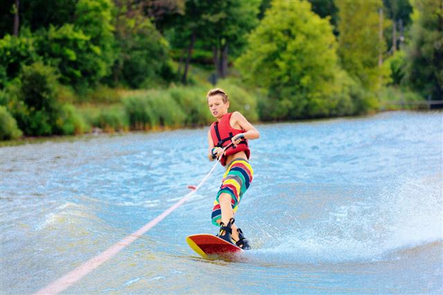 Active Boy Water Ski Boarding On Lake