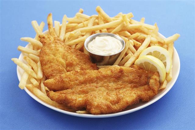 A closeup of a fish and chips platter with dipping sauce