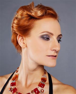 Young beautiful red-haired girl with chiseled cheekbones in designer jewelry