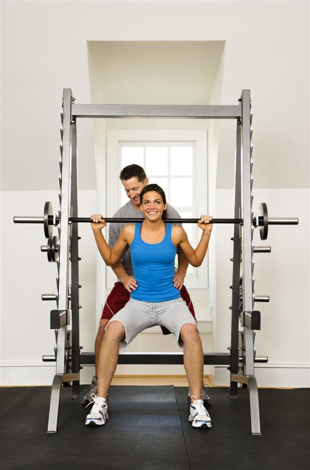 Woman Lifting Weights With Trainer