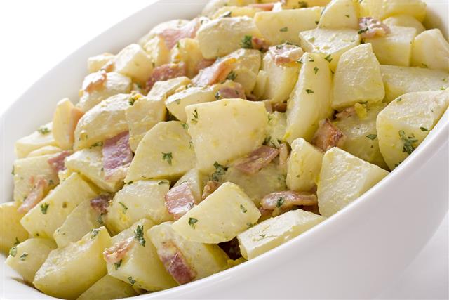A German potato salad in a white bowl with seasoning