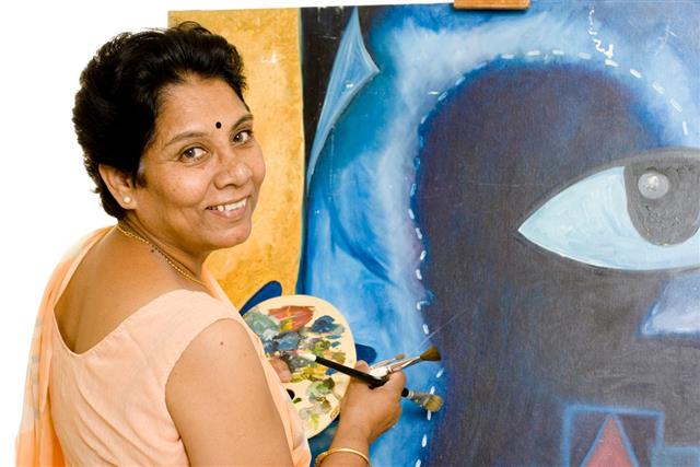 One Cheerful Indian Senior Woman Artist Working on her Painting