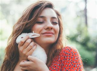 Young woman holding a little white bunny at nature