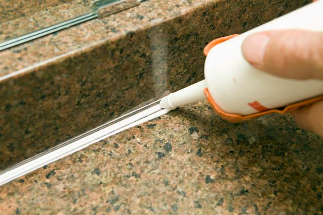Calk Gun Applying Silicone to Granite Sink