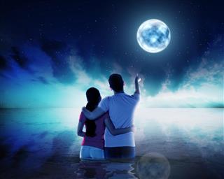 Young couple pointing moon at night time