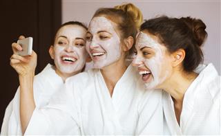 Three young happy women with face masks at spa resort