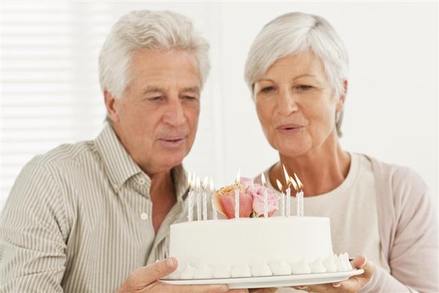 Senior couple holding anniversary cake