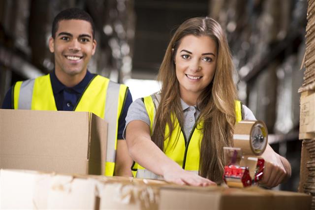 Young warehouse workers packing boxes