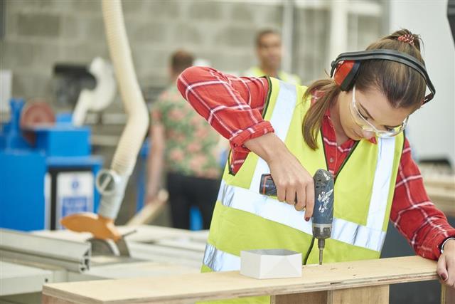 Female carpenter screwing her work together