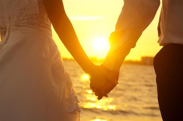 Holding hands in front of a sunset