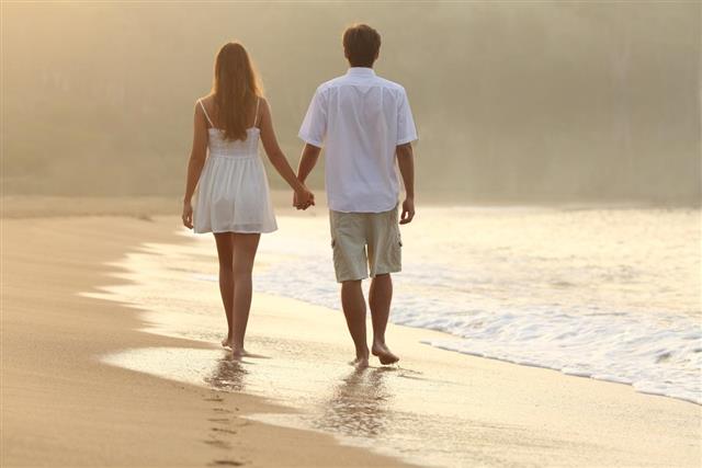 Couple walking and holding hands on the sand