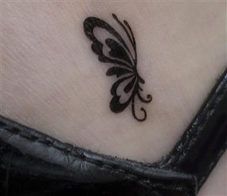 Very small butterfly tattoo on woman's ankle