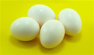 Four white eggs on yellow background