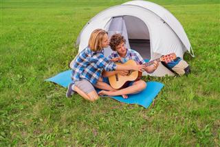 Couple near the tent play guitar