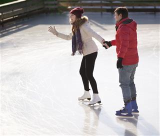 Young Couple Ice Skating Outdoors