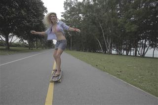 blonde woman skateboarding down