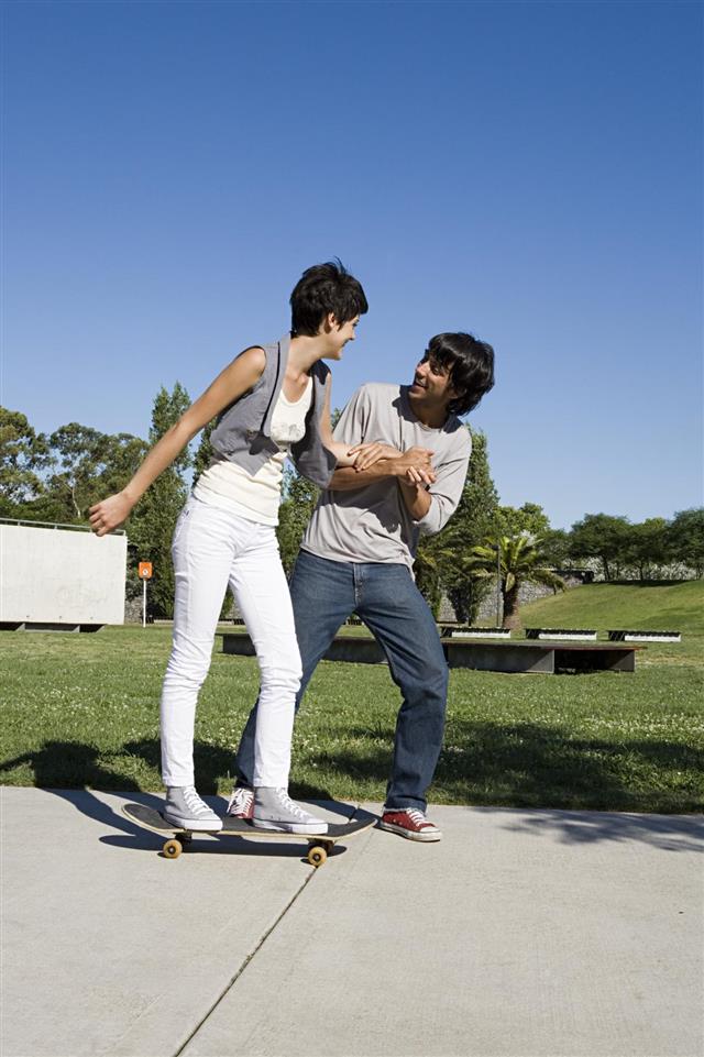 man helping girl to skateboard