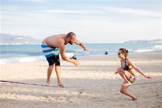 Teenage Couple Balancing Slackline On Beach