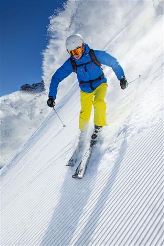 Skier Skiing Downhill In High Mountains
