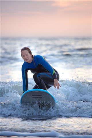 Middle Aged Female Surfing At Dusk