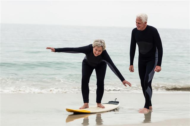 Senior Man Teaching Woman To Surf