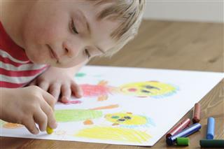 Boy Drawing On White Paper With Crayons