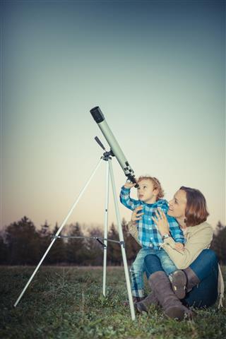 Mother and son looking through a telescope outdoors