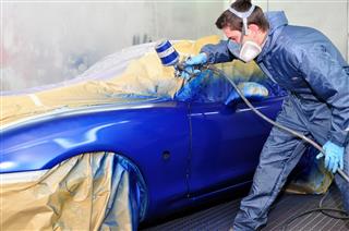 Male Worker Painting Exterior Of Car