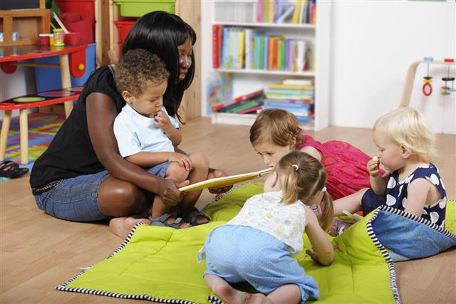Carer Reading To A Group Of Toddlers At Nursery
