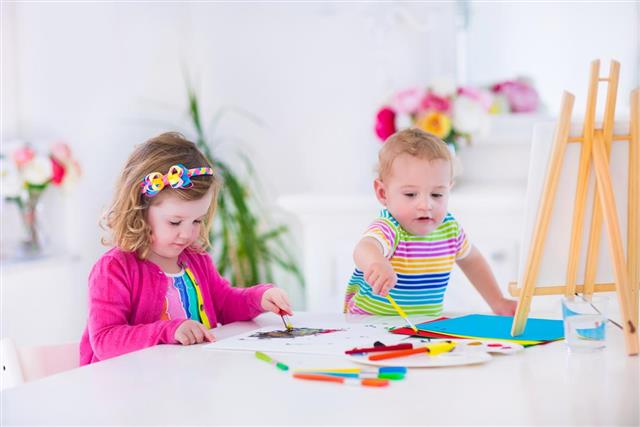 Children painting on wooden easel