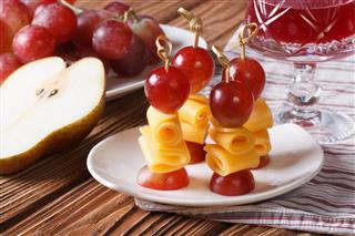 Red grapes and cheese on skewers and glass of wine