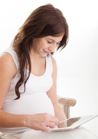 Pregnant brunette using a digital tablet