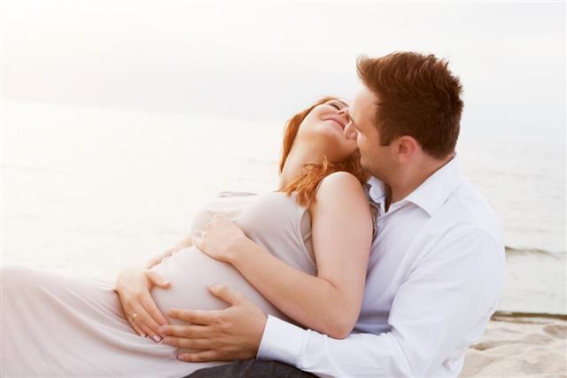 Pregnant woman with her husband on the beach