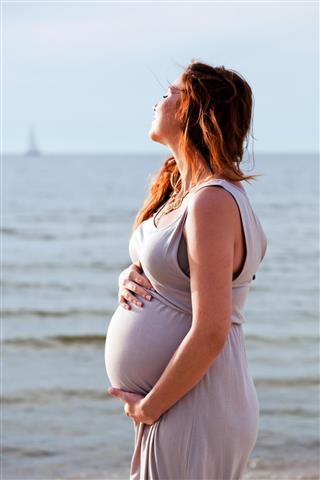 Young beautiful pregnant woman on the beach