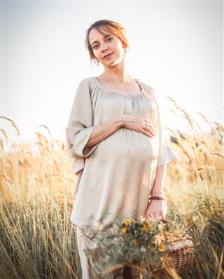 Young beautiful pregnant woman walking in a field