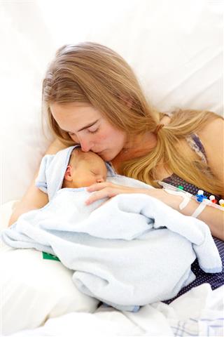 Young woman holding her sleeping 1 day old daughter