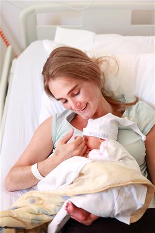 Young woman holding her sleeping 5 days old daughter