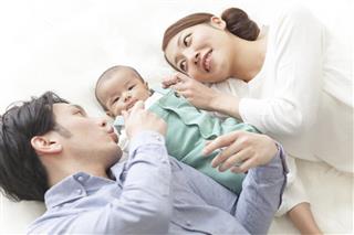 Japanese couple lying with baby between them