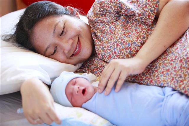 Happy woman looking at her newborn baby