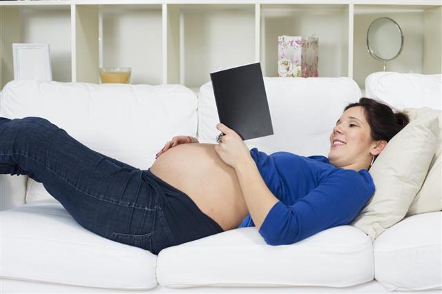 Smiling pregnant woman relaxing and reading book