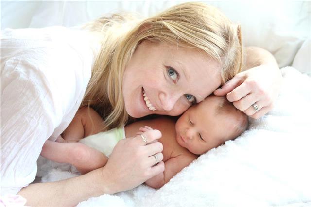 Happy Young Mother Snuggling her Newborn Baby Girl