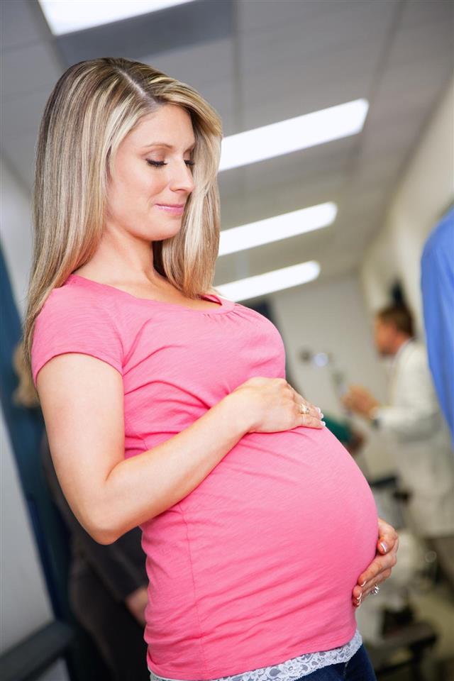 Pretty pregnant woman holding belly in hospital